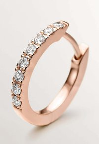 Anillo de aro en oro rosa con una fila de siete piedras redondas de zirconia cúbica clara engastadas en un diseño de garras a lo largo del borde frontal.