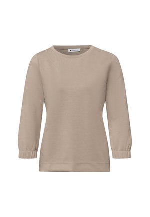 Beige Damenbluse mit langen Ärmeln, rundem Halsausschnitt und elastischen Bündchen, schlichtes Design, auf weißem Hintergrund dargestellt.