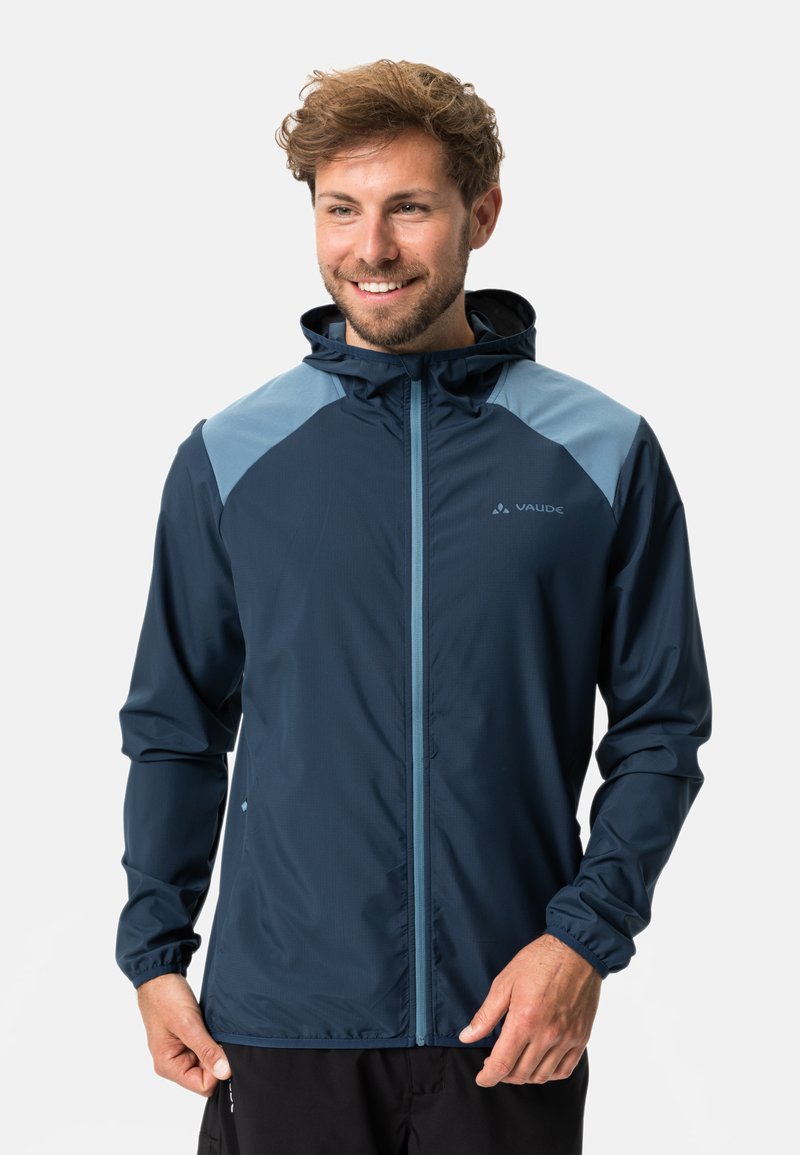 Marineblaue Regenjacke mit hellblauen Akzenten, durchgehendem Reißverschluss, verstellbarer Kapuze und elastischen Bündchen. Leichtes Gewebe mit glatter Textur.