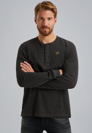 T-shirt henley noir à manches longues avec trois boutons et un petit patch logo rectangulaire sur la poitrine. Tissu doux avec une coupe décontractée.