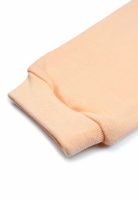 Pfirsichfarbener, gestrickter Ärmelbund mit geripptem Muster, der eine glatte Oberfläche und kontrastierende Nahtdetails aufweist. Weiches, flexibles Material.