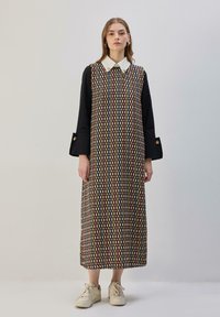 Maxi suknelė juodu pagrindu su margu geometriniu raštu, su apykakle ir ilgomis rankovėmis su sagų detalėmis.