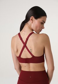 Sportivo color marrone con design incrociato delle spalline sul retro, realizzato in tessuto morbido con spalline regolabili e chiusura a gancio.