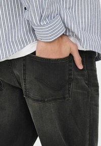 Mørke denim jeans med et klassisk fem-lomme design, med en subtil buet syning på baglommen og en glat tekstur.
