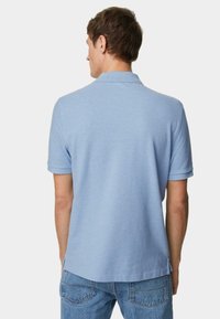 Himmelblaues Poloshirt mit umgeschlagenem Kragen und kurzen Ärmeln, aus weichem Stoff gefertigt. Die Rückansicht zeigt seitliche Schlitze und schlichte Nähte.