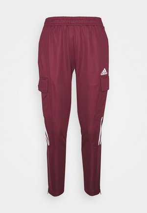 Bordowe spodnie dresowe Adidas z elastycznym pasem, kieszeniami cargo po bokach, białym logo Adidas na prawej udzie oraz białymi paskami w okolicy łydek.