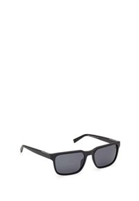 Occhiali da sole neri rettangolari con lenti scure, montatura opaca e lati texturizzati. Presentano un logo discreto sulle astine.