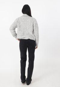 Szary, puszysty sweter z wysokim kołnierzem, noszony na czarnych spodniach o prostym kroju. Sweter ma skróconą formę i żeberkowy dół.