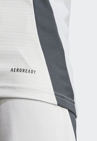 AEROREADY atletisk skjorte i hvid og mørkegrå, med et struktureret mønster, kontrasterende farveblokke og syede detaljer.