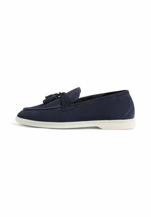 Marineblaue Wildleder-Slipper mit abgerundeter Zehenform, dekorativen Quasten und einer kontrastierenden weißen Gummisohle. Glatte Textur und minimalistisches Design.