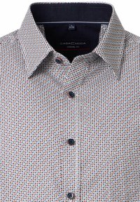 Koszula o casualowym kroju z białą bazą i kolorowym wzorem liści w czerwieni, niebieskim i czerni. Klasyczny kołnierz i ciemne guziki.