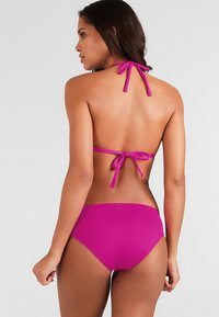 Bikini de color rosa brillante con un cuello halter y tiras ajustables, junto con unas braguitas de tiro bajo a juego. Textura suave con mínimo herrajes.