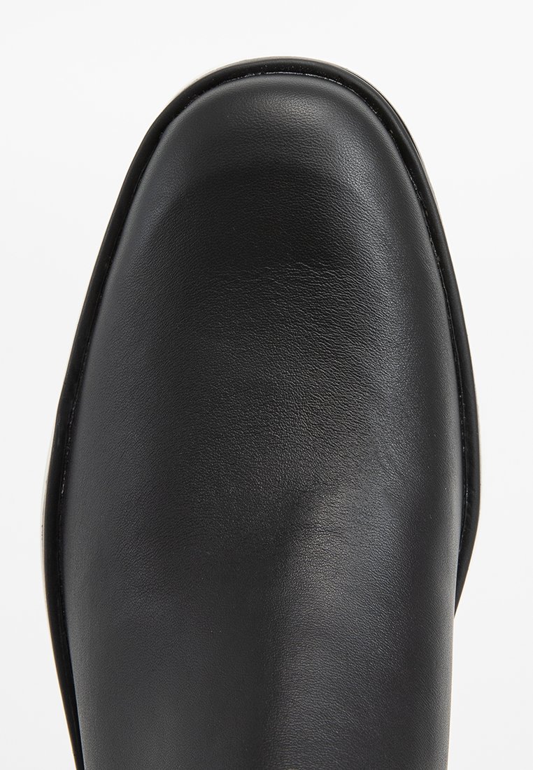 Schwarzer Lederschuh mit einer glatten, runden Zehenpartie und einem klaren Design. Die Oberfläche ist gleichmäßig und zeigt einen subtilen Glanz sowie eine Stickdetail.