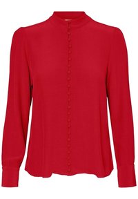 Röd blus med hög krage, långa ärmar och knappstängning fram med runda knappar. Mjuk, texturerad tyg för komfort.