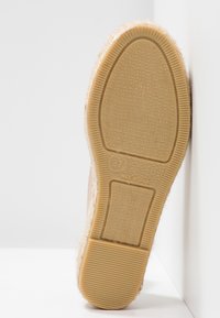 Suela de goma en color marrón claro con una superficie texturizada y con patrón. El borde cuenta con un trim textil suave y peludo. Talla 37, marcado "Hecho en España."