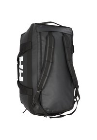 Black duffel bag made of durable material, featuring padded shoulder straps, top handle, and large white logo on the side.