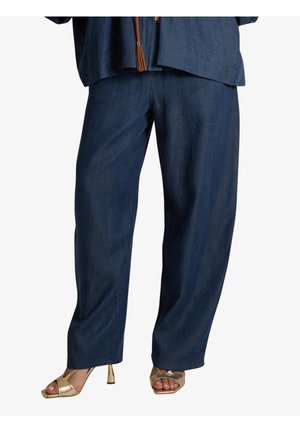 Pantaloni larghi blu scuro indossati con sandali dorati con tacco alto e dita scoperte, abbinati a un top blu coordinato con un dettaglio di nappine marrone.
