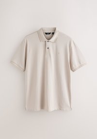 Polo beige clair à manches courtes avec deux boutons et bordure rayée subtile au col et aux poignets, présenté sur fond uni.