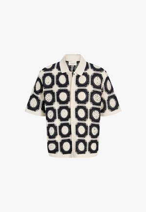 Lühikeste varrukatega kraega särk, millel on mustade ja kreemjate heegeldatud ruutude mustrid, mis kujutavad ringikujulisi lillemustreid, ning nööbitav eesmine osa.