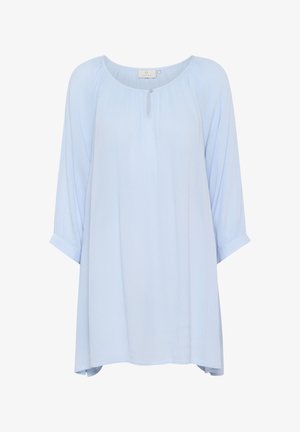 Blouse bleu clair, ample, avec un col rond, des boutons sur le devant, des détails plissés et des manches 3/4 roulées aux poignets. Texture douce.
