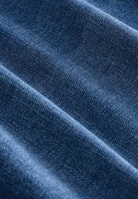Tejido de mezclilla azul texturizado con un acabado suave, que presenta una canaladura diagonal y sutiles variaciones en color y sombra.