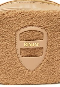 Pochette in tessuto beige con una superficie texturizzata e un accento in pelle liscia, dotata di un logo color oro. Chiusura con zip lungo il bordo superiore.