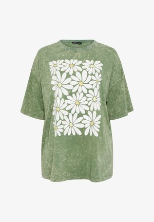 Groen acid-wash T-shirt met korte mouwen en een vierkant patroon van witte madeliefjes met gele middens aan de voorkant.
