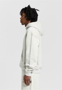 Light gray hoodie made of a soft material with a front pocket, long sleeves, and a drawstring hood, featuring ribbed cuffs and hem.
