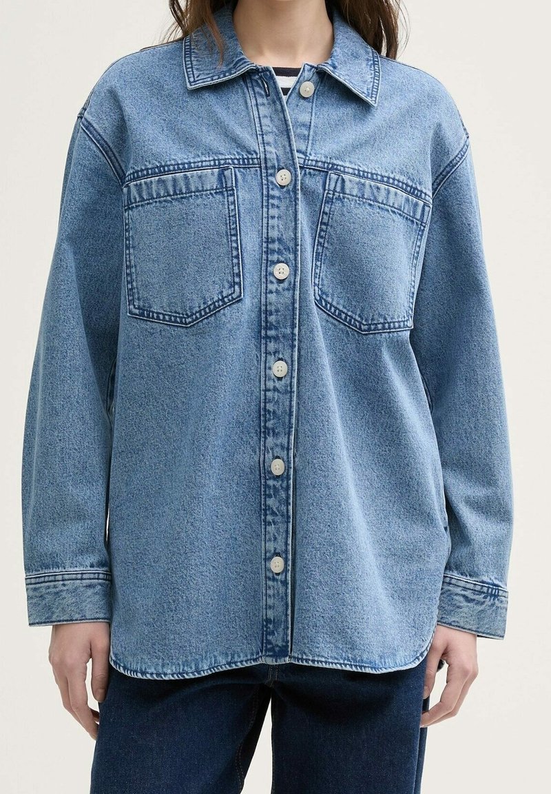 Denimskjorte i lyseblå, med knaplukning foran, to brystlommer og en afslappet pasform med en rund kant og lange ærmer.