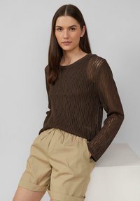 Haut en tricot marron à manches longues avec une texture côtelée, associé à un short beige clair, doté d'une taille élastique et de manches retroussées.