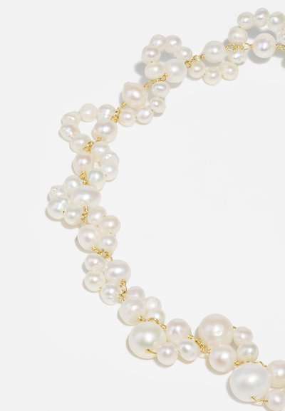 Πετράδι από πέρλες με ποικιλία στρογγυλών, λευκών πέρλων που διαθέτουν λεία υφή, διασυνδεδεμένες με αλυσίδα σε χρυσό τόνο.