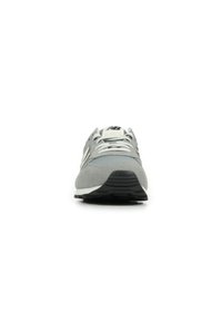 Scarpa da ginnastica grigia con tomaia in suede e rete, dettagli bianchi, punta arrotondata, lacci e suola in gomma nera.