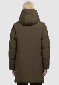 Duga, maslinasto zelena puffer jakna s kapuljačom. Ima kvadratni uzorak, elegantan dizajn i ravni kroj, završava ispod bokova.