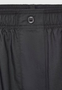 Pantalones cortos de tela negra con cintura elástica y cierre de botón. Presentan una textura suave y un acabado liso. Detalles cosidos a lo largo de las costuras.