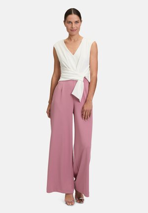 Top bianco a wrap con scollatura a V profonda e maniche corte abbinato a pantaloni rosa a vita alta e gamba larga. Tessuto morbido, dettagli minimi.