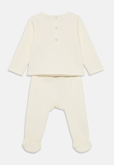 Deltid baby outfit i kremfarge; inkluderer en langermet topp med tre knapper bak og matchende foted bukser med rynkete mansjetter.