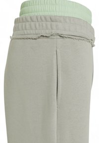 Lichtgrijze joggers met een geplooide mintgroene tailleband, voorzien van een rafelige rand bovenaan. Zacht katoenen materiaal met zijzakken.