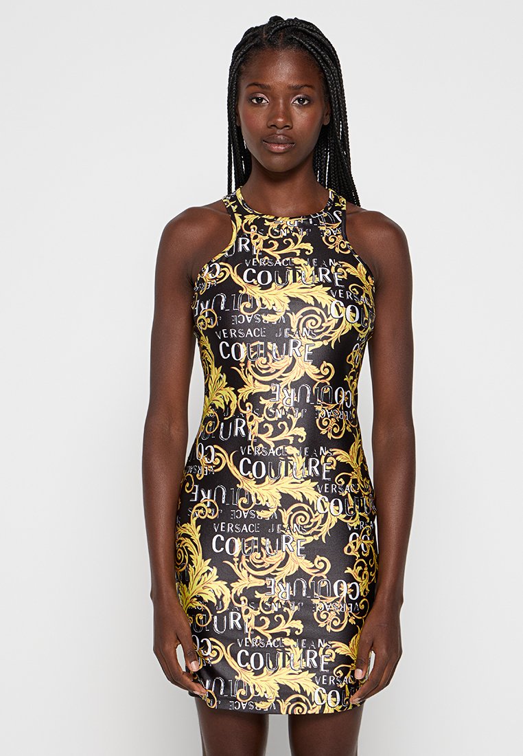 Czarna sukienka o dopasowanym kroju z żółtymi i białymi logo Versace oraz skomplikowanymi złotymi wzorami kwiatowymi na całej powierzchni.