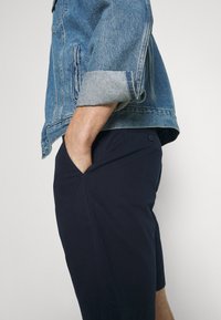 Denimjacka i ljusblått med uppvikta ärmar och två sidfickor, kombinerad med marinblå shorts med en sidficka och knapppdetalj.