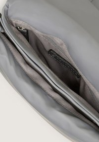 Interno di una borsa per laptop grigia con un grande scomparto, una tasca con zip e una fodera in tessuto morbido con un dettaglio etichetta.