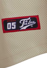 Tessuto beige perforato con una toppa rossa e nera che mostra la scritta "OFFICIAL 05 Fubu" in carattere corsivo bianco. Include un bordo cucito.