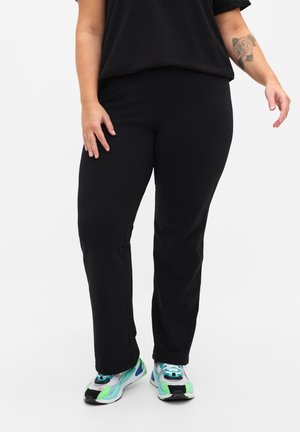 Black, slim-fit pants made from a soft fabric, with a plain design and slight stretch. Paired with colorful athletic shoes featuring mesh details.