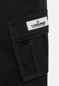 Svarta cargo-byxor med kontrasterande bruna sömmar, som har en stor sidoficka och en märkeslogotyp i vit tygsömpatch med "VINGINO".