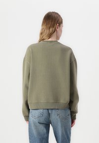 Olijfgroen sweatshirt met een relaxte pasvorm, geribde boorden en een zoom. Gemaakt van zachte stof, met een ronde halslijn en verlaagde schouders.