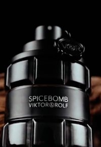 Flacon de parfum cylindrique noir avec une surface texturée, portant "SPICEBOMB VIKTOR & ROLF" en blanc. Le bouchon est orné d'un emblème noir.