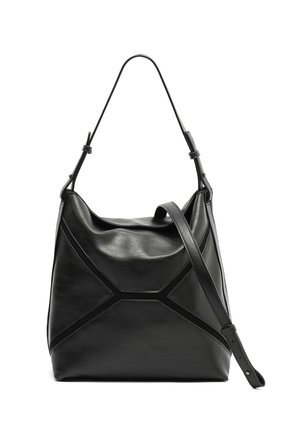 Črna usnjena torbica za ramo z enim zgornjim ročajem, geometrijskim vzorcem šivov in nastavljivim trakom za nošenje čez ramo na belem ozadju.