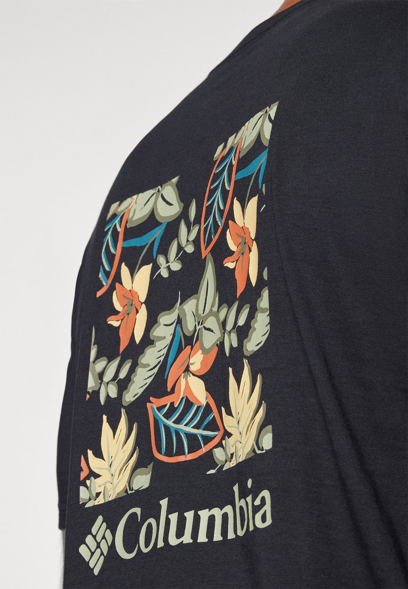 Camiseta azul marino oscuro con un estampado floral en verdes, naranjas y amarillos, con el logo de "Columbia" en verde claro en la parte inferior.