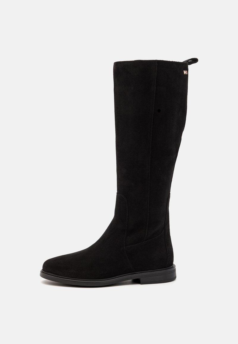 Botte noire en daim montant au genou avec une texture lisse, un bout arrondi et des coutures minimalistes. Présente un petit logo près du sommet.