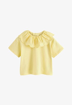 Gul bomulds-T-shirt med korte ærmer, der har en bølget øjeltblondekrave og knaplukning bagpå. Enkel og let design.