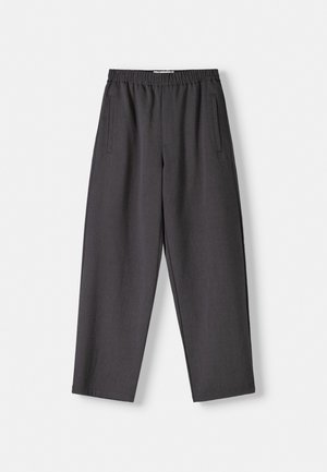 Pantalon gris à coupe décontractée, avec une taille élastique et deux poches latérales. Le tissu semble lisse avec une texture subtile.